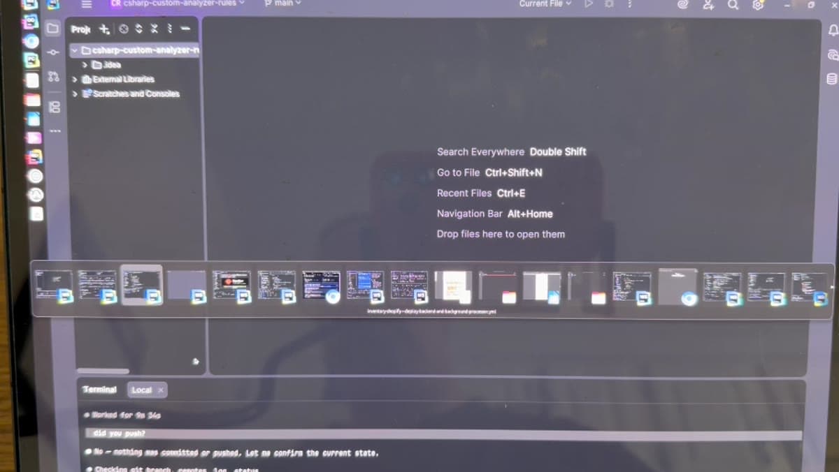 A JetBrains IDE open on a C# analyzer rules project over remote desktop, with a window switcher overlay and a terminal at the bottom showing an AI agent replying to a question about whether it pushed